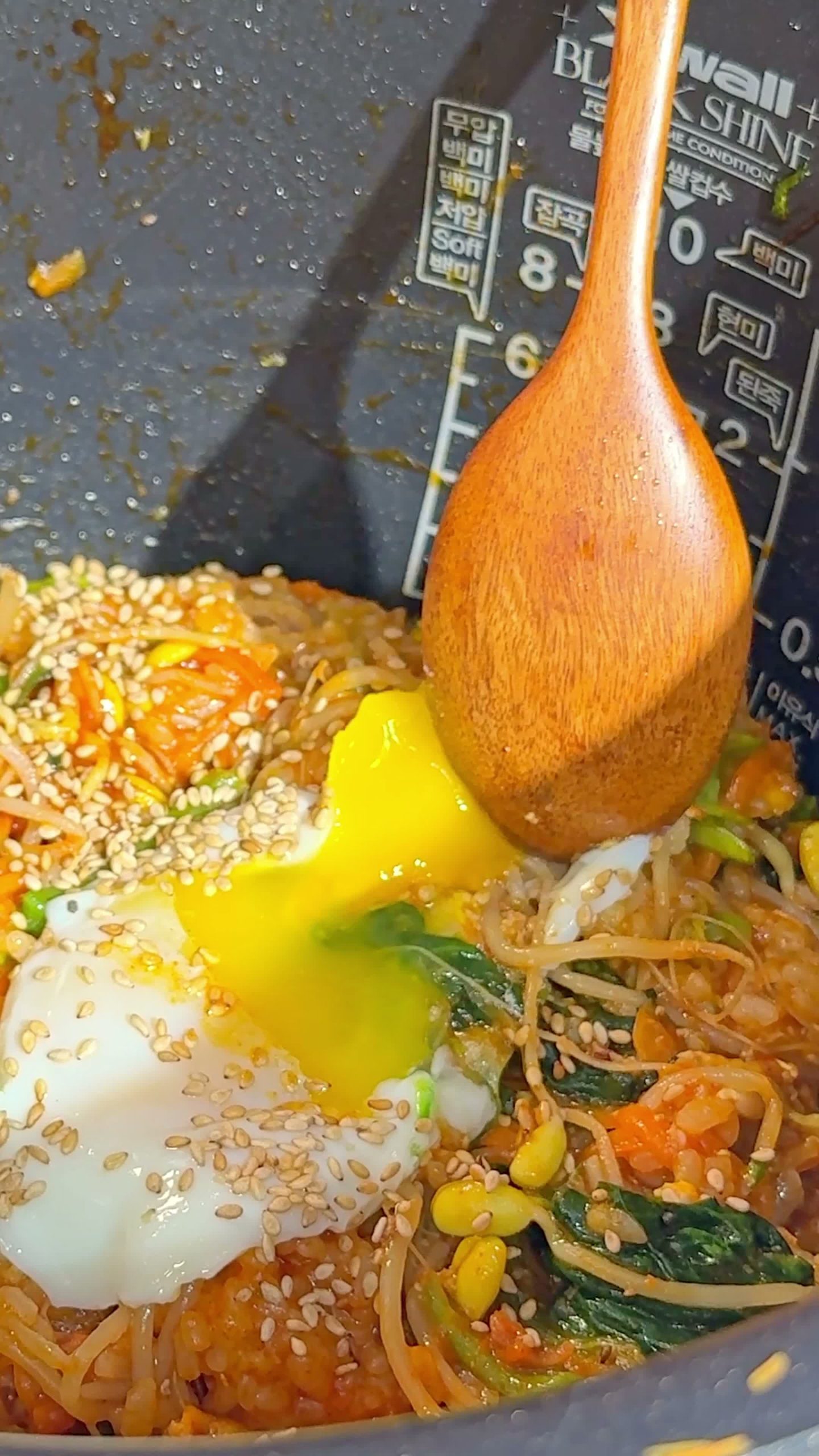 Mixing the finished bibimbap with a wooden spoon