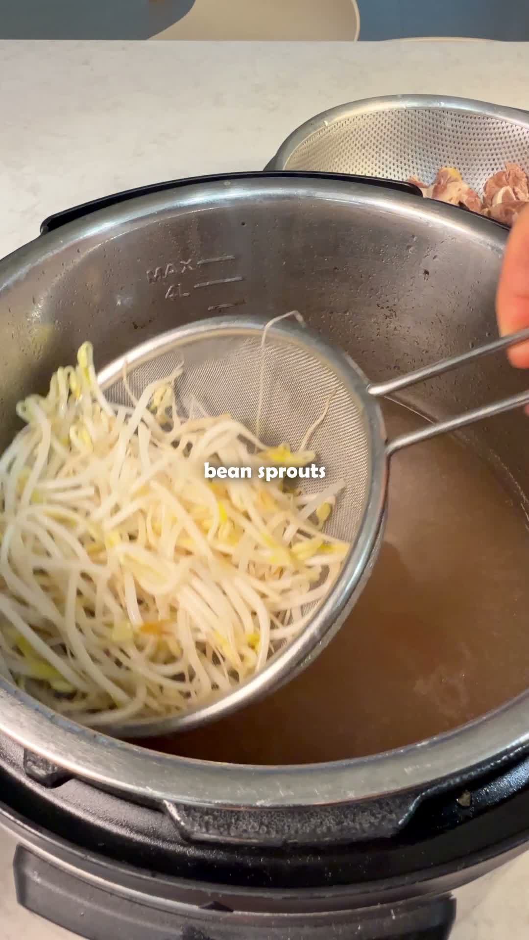 Bean sprouts being lifted from the blanching broth
