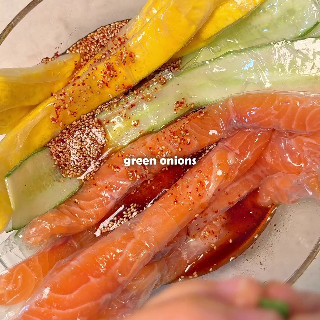Salmon, cucumber, and egg strips laid out with green onions