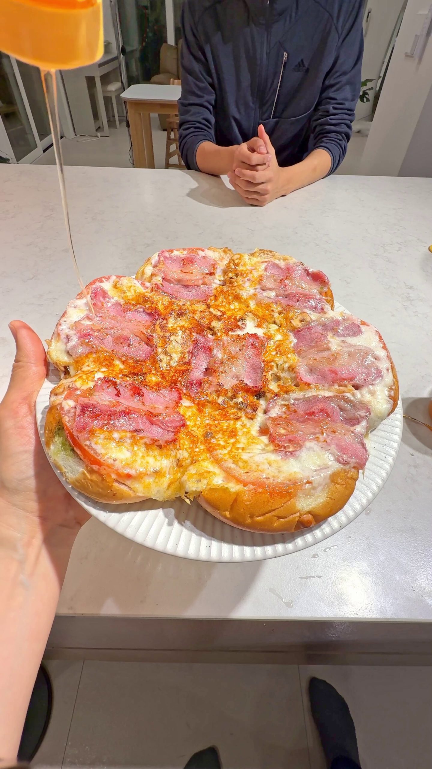 Dinner roll pizza topped with bacon, walnuts, cheese, and tomato