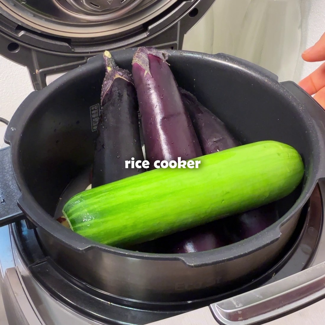 Whole eggplants placed on top of rice in the rice cooker
