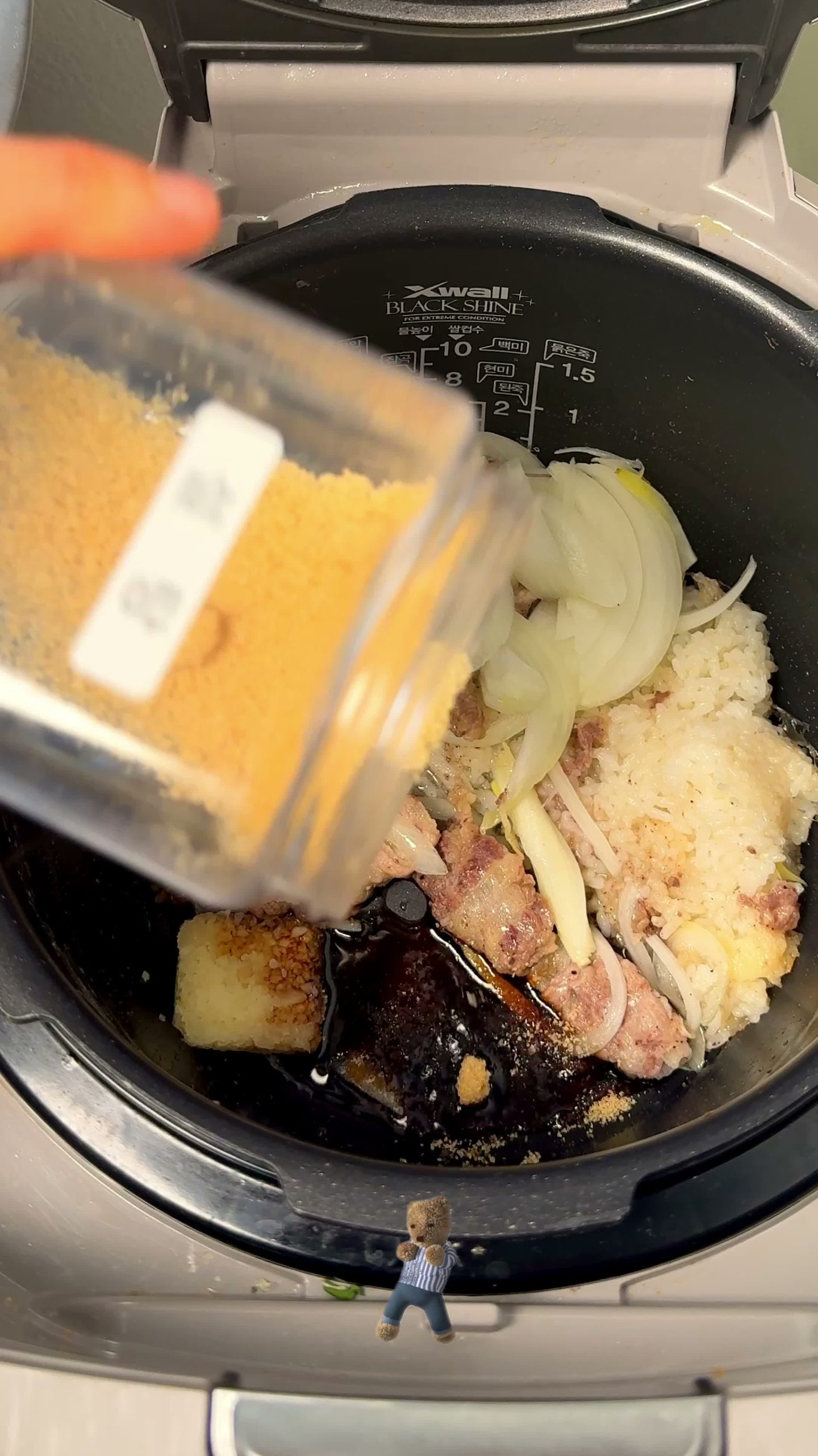Soy sauce and sugar being poured over the beef and onion