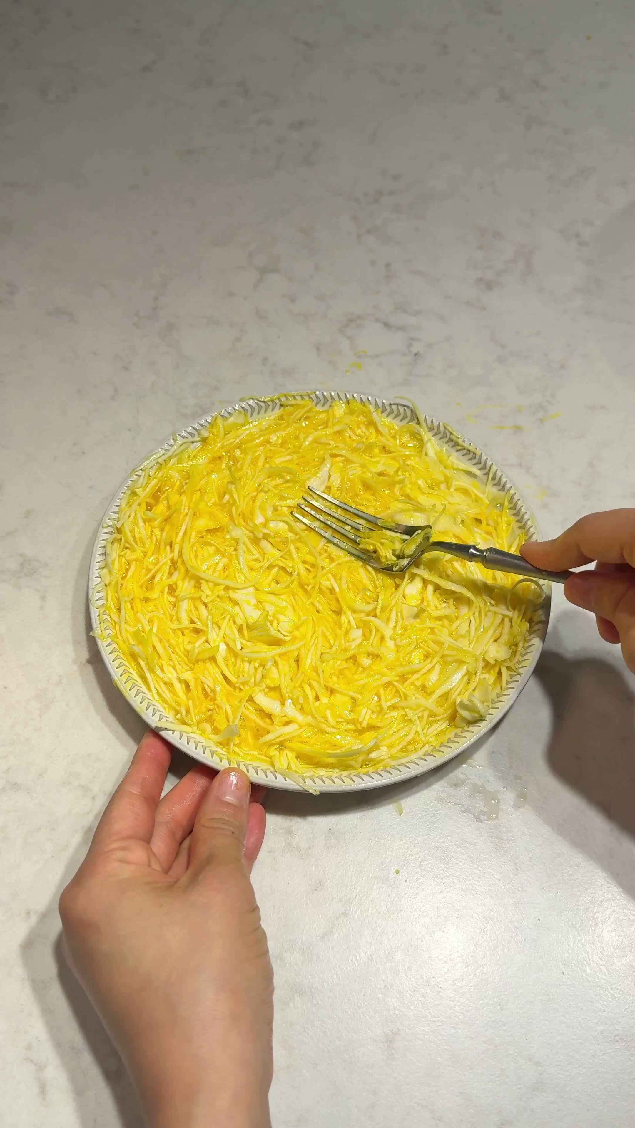 Mixing eggs with shredded cabbage on a plate