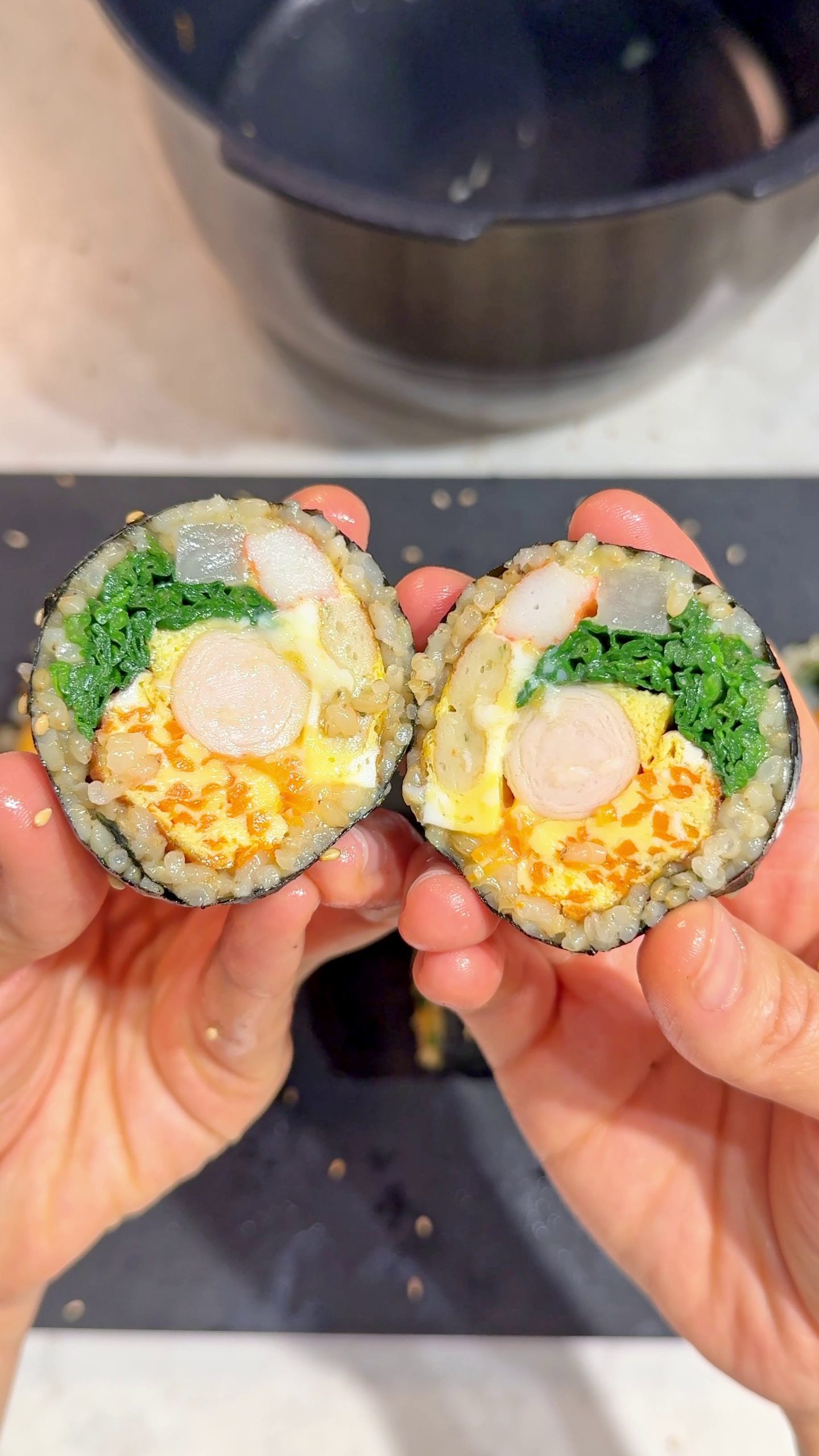 Kimbap cross-section showing egg, crab stick, carrot, and spinach filling