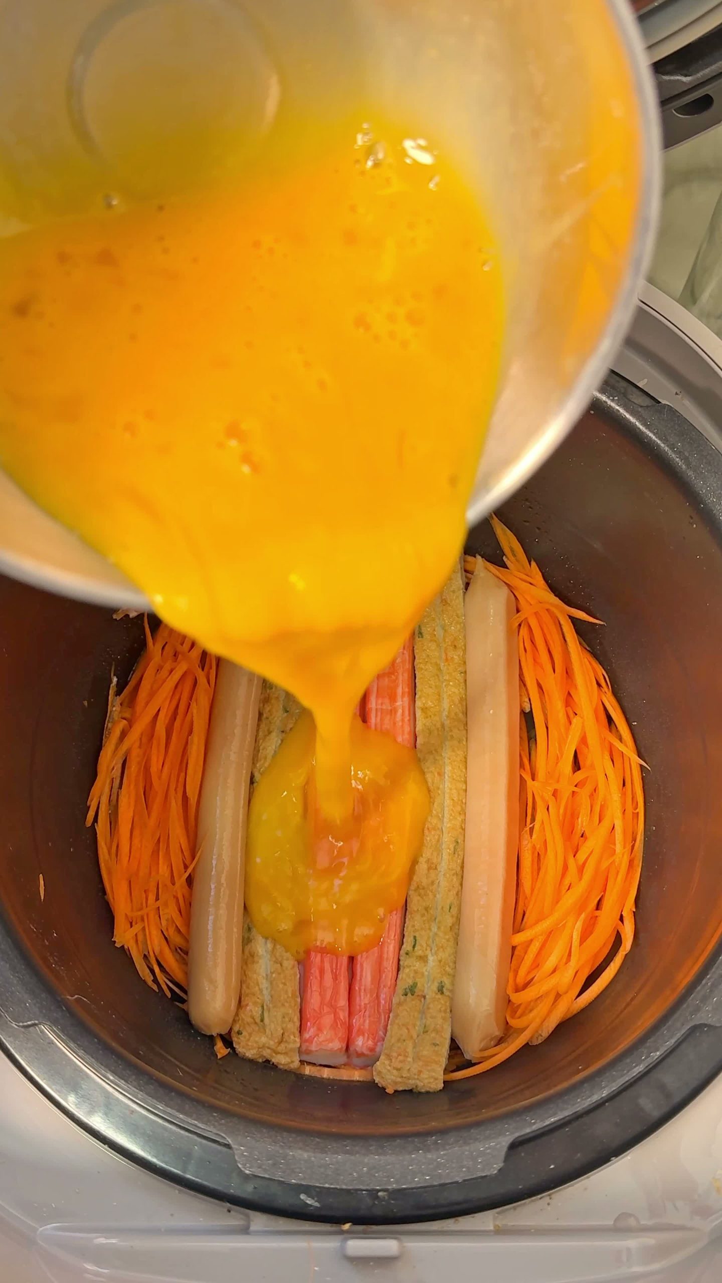Carrots, crab sticks, ham, and egg arranged on a steamer tray