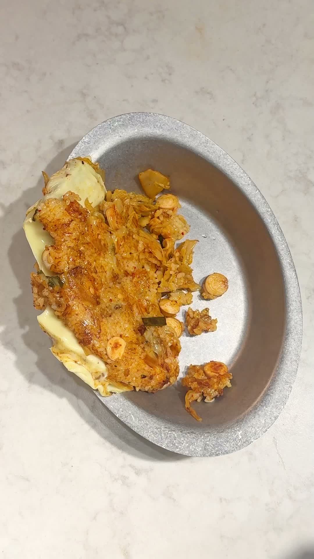 Finished kimchi fried rice with cheese folded in, topped with eggs