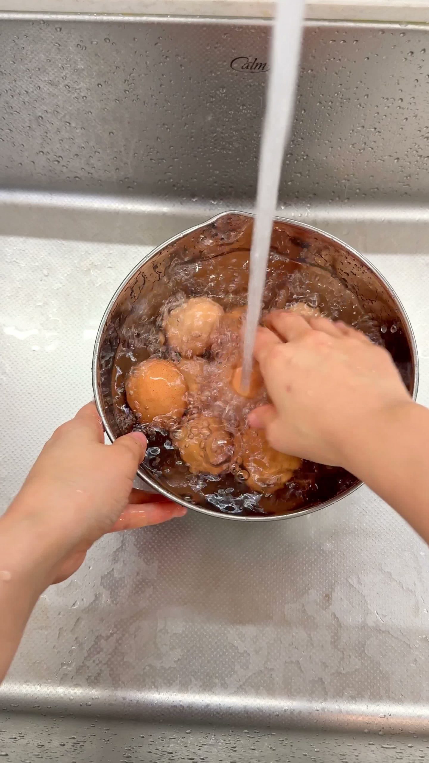 Eggs in an ice bath being peeled under running water