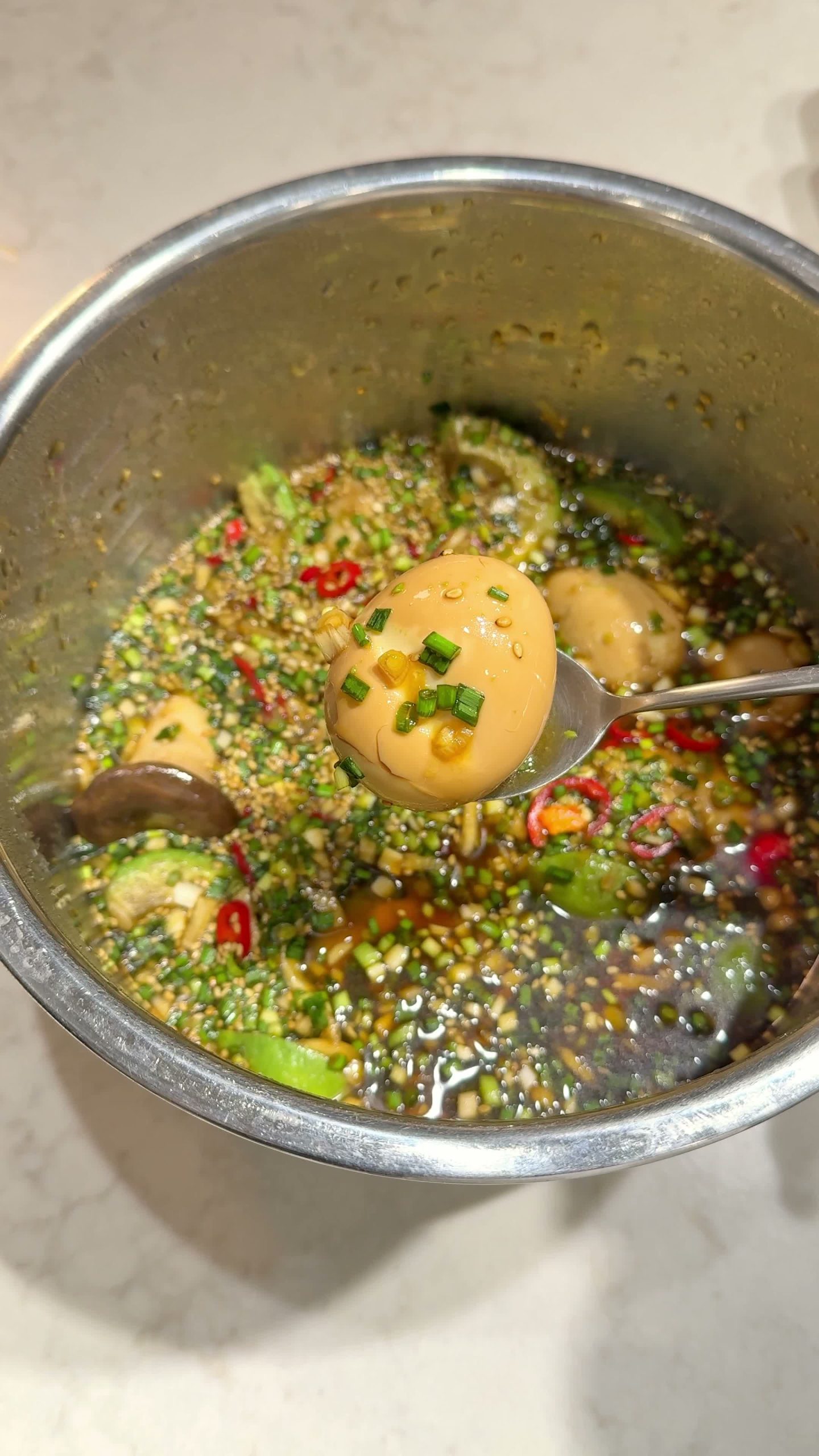 Mixing the peeled eggs, mushroom, and avocado into the marinade