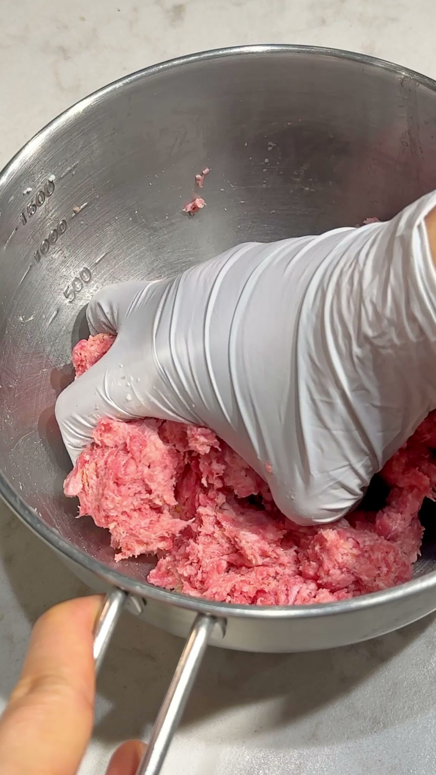 Kneading the bread, milk, and ground beef mixture by hand