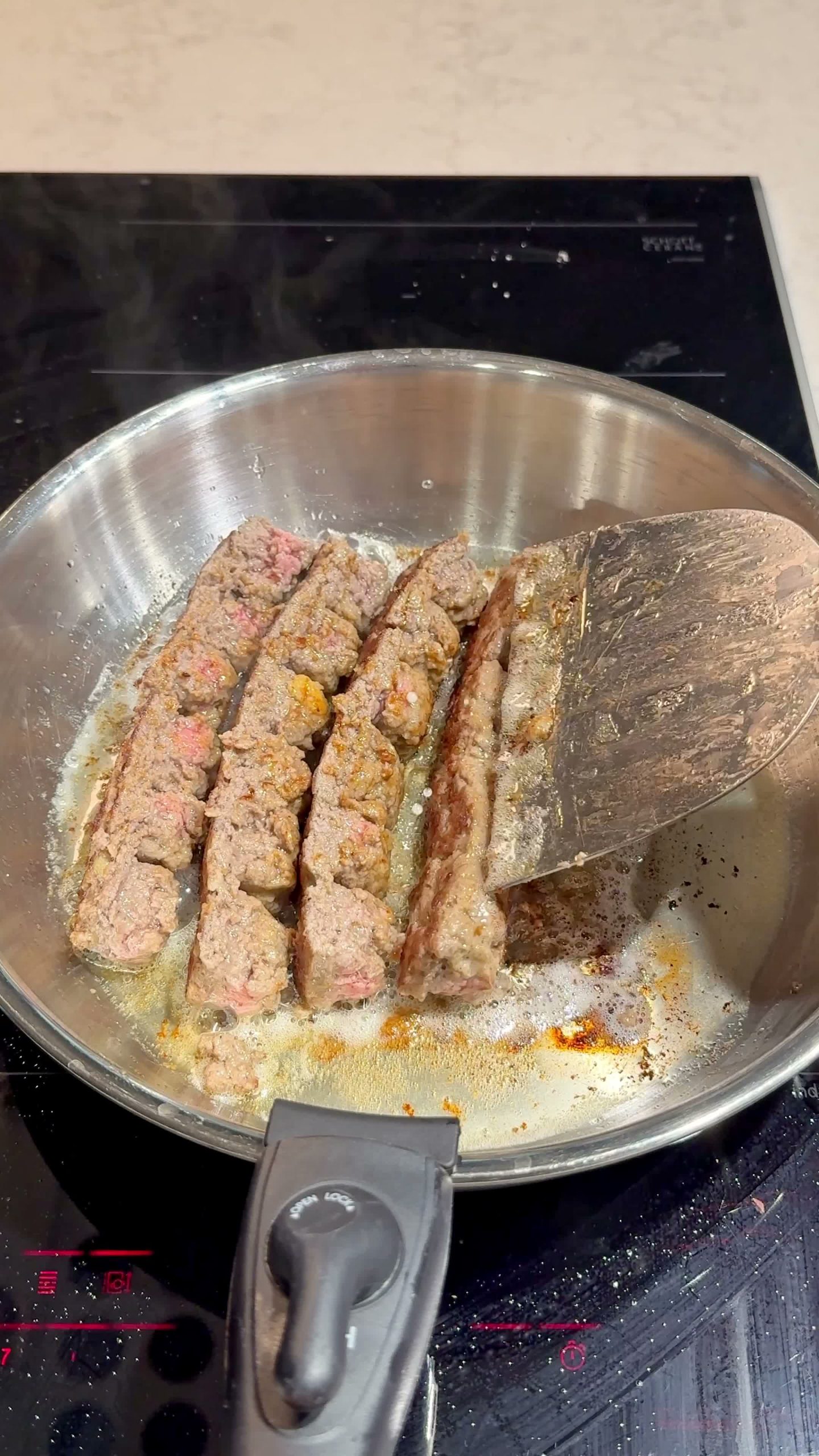 Meatballs cooking in the pan after the tray is removed