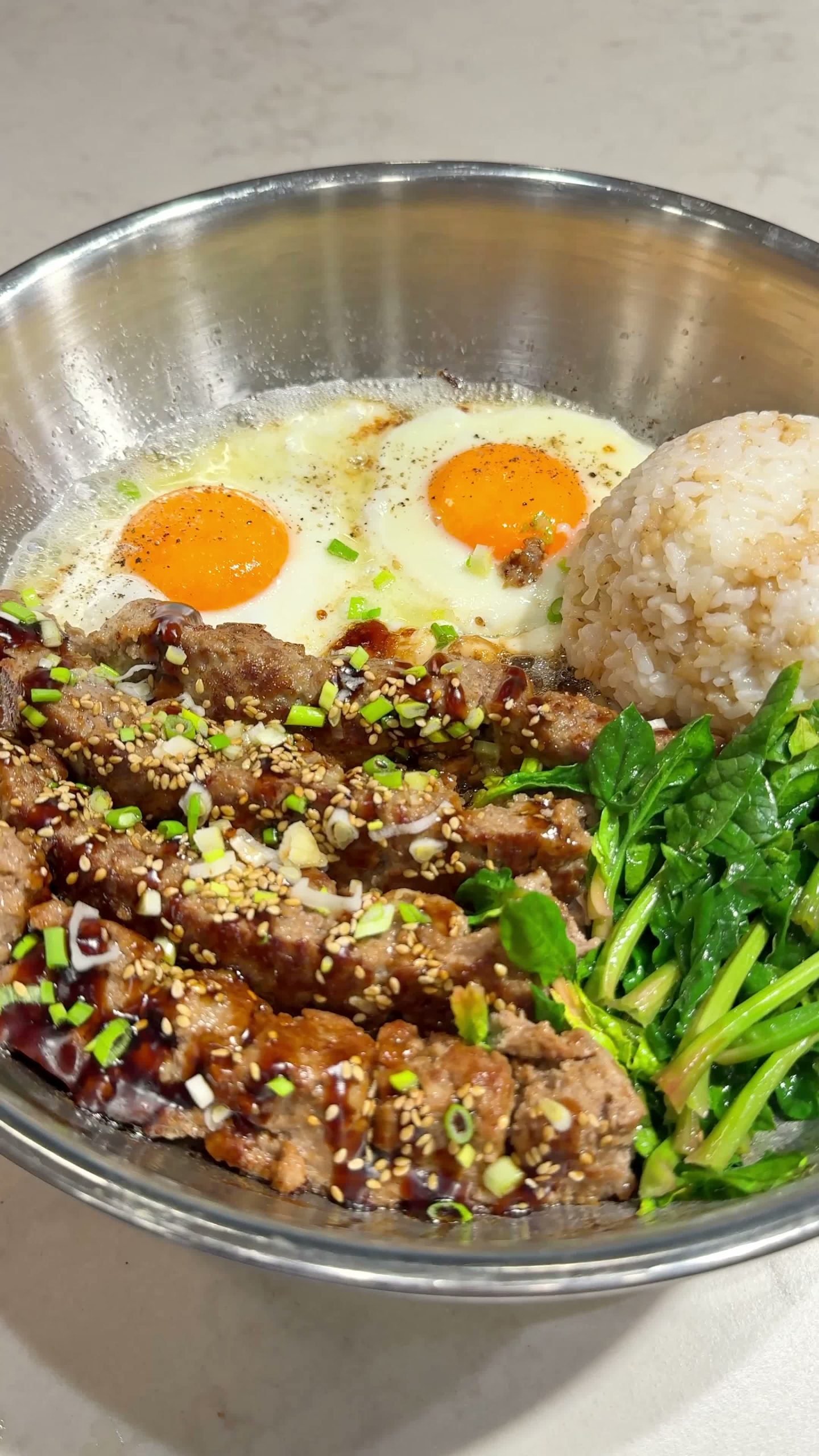 Finished meatballs, eggs, and rice topped with teriyaki sauce and greens
