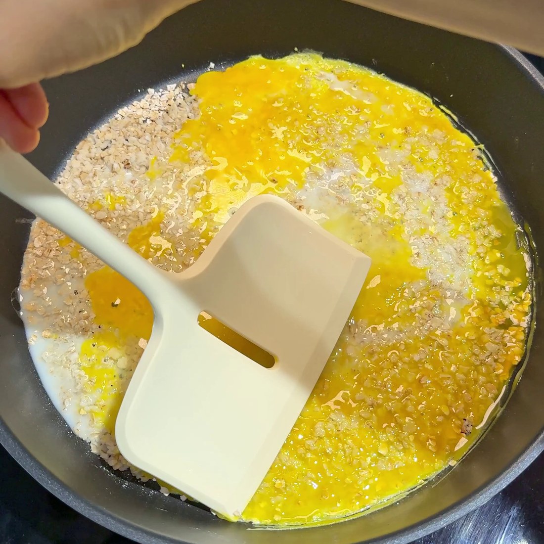 Two eggs cracked and spread over the oatmeal