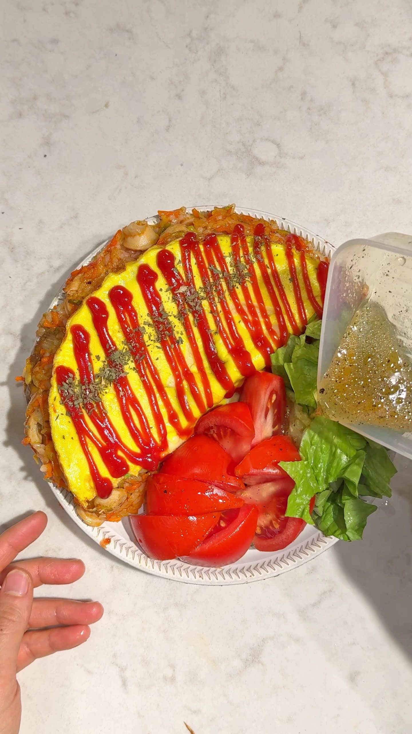 Omurice with egg on top drizzled with ketchup, cut into portions with tomato and lettuce