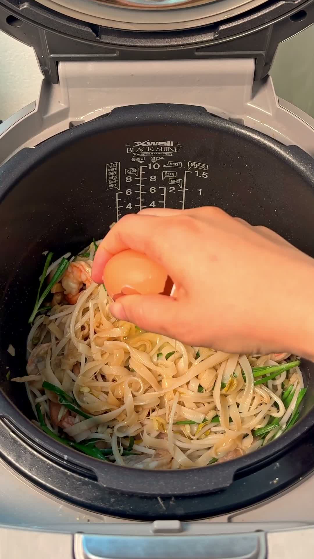 Egg cracked on top of the noodles with garlic chives