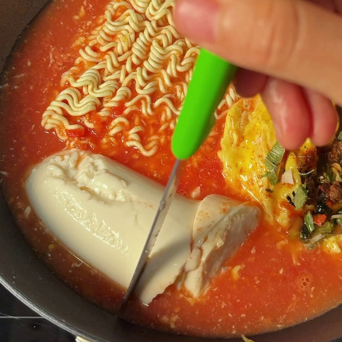 Ramen noodles and soft tofu added to the simmering pan