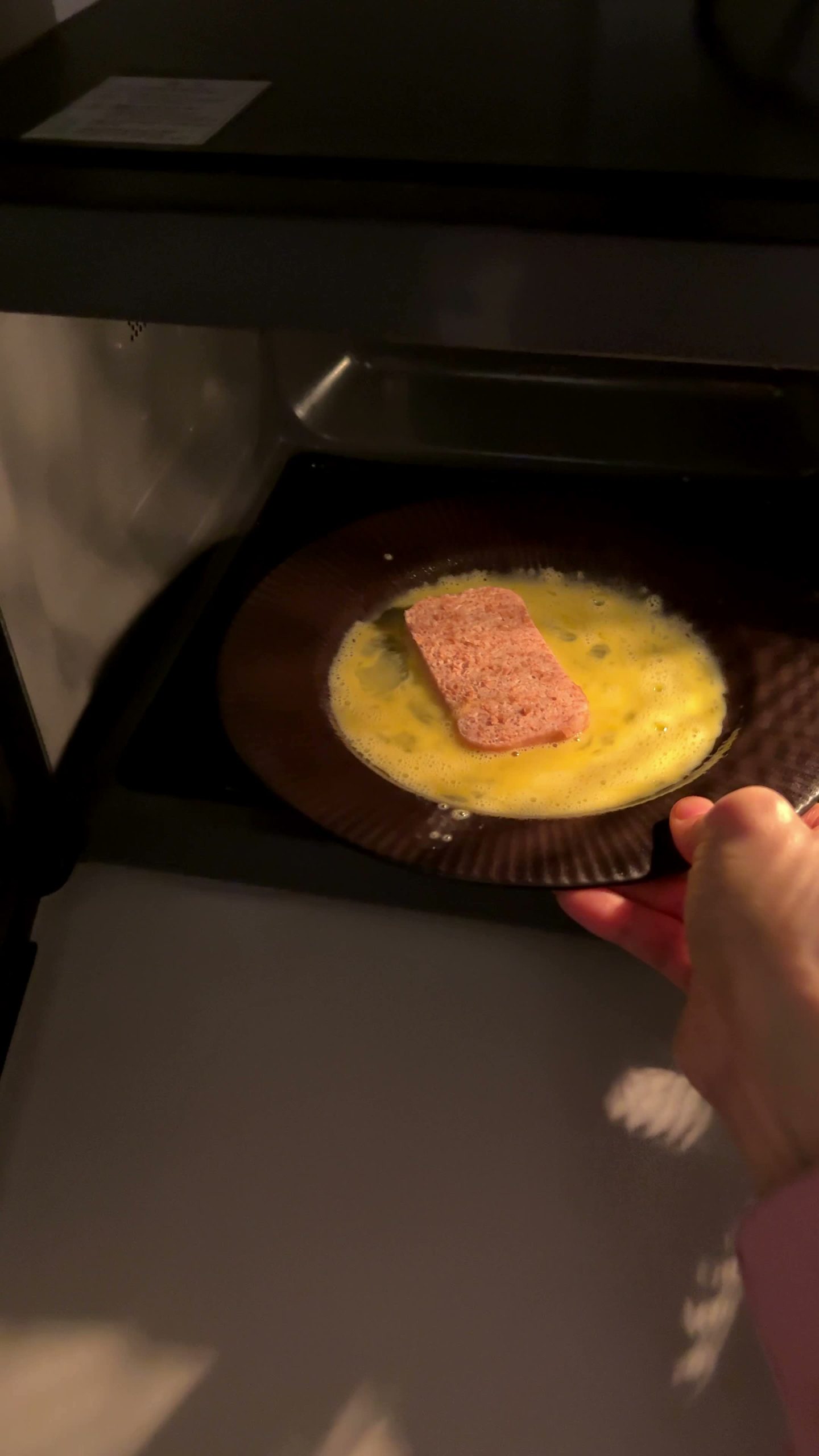 Ham and egg on a plate cooking in the microwave
