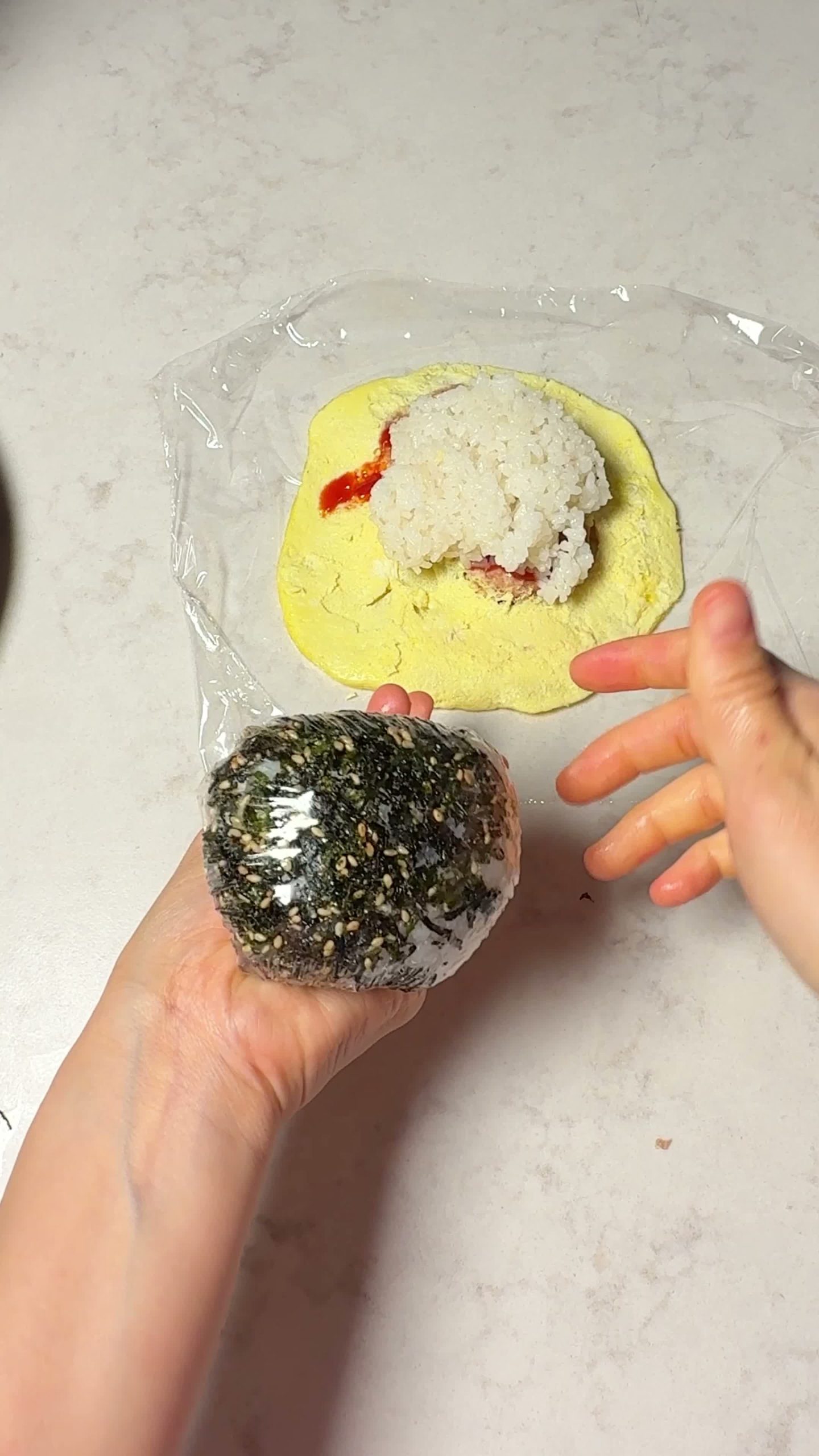 Gathering and twisting the wrap to shape the rice ball