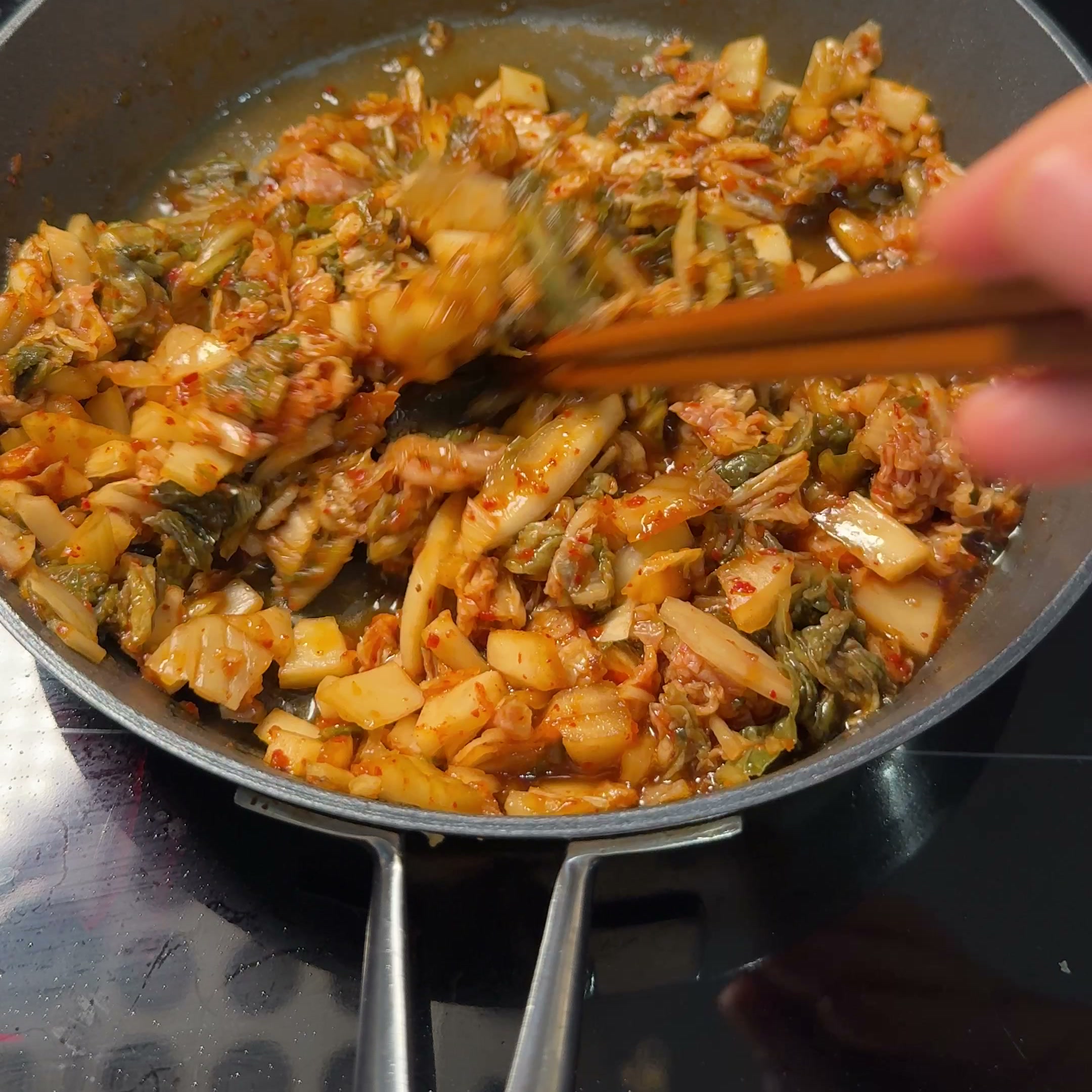 Chopped kimchi sautéing in the pan, stirred with chopsticks