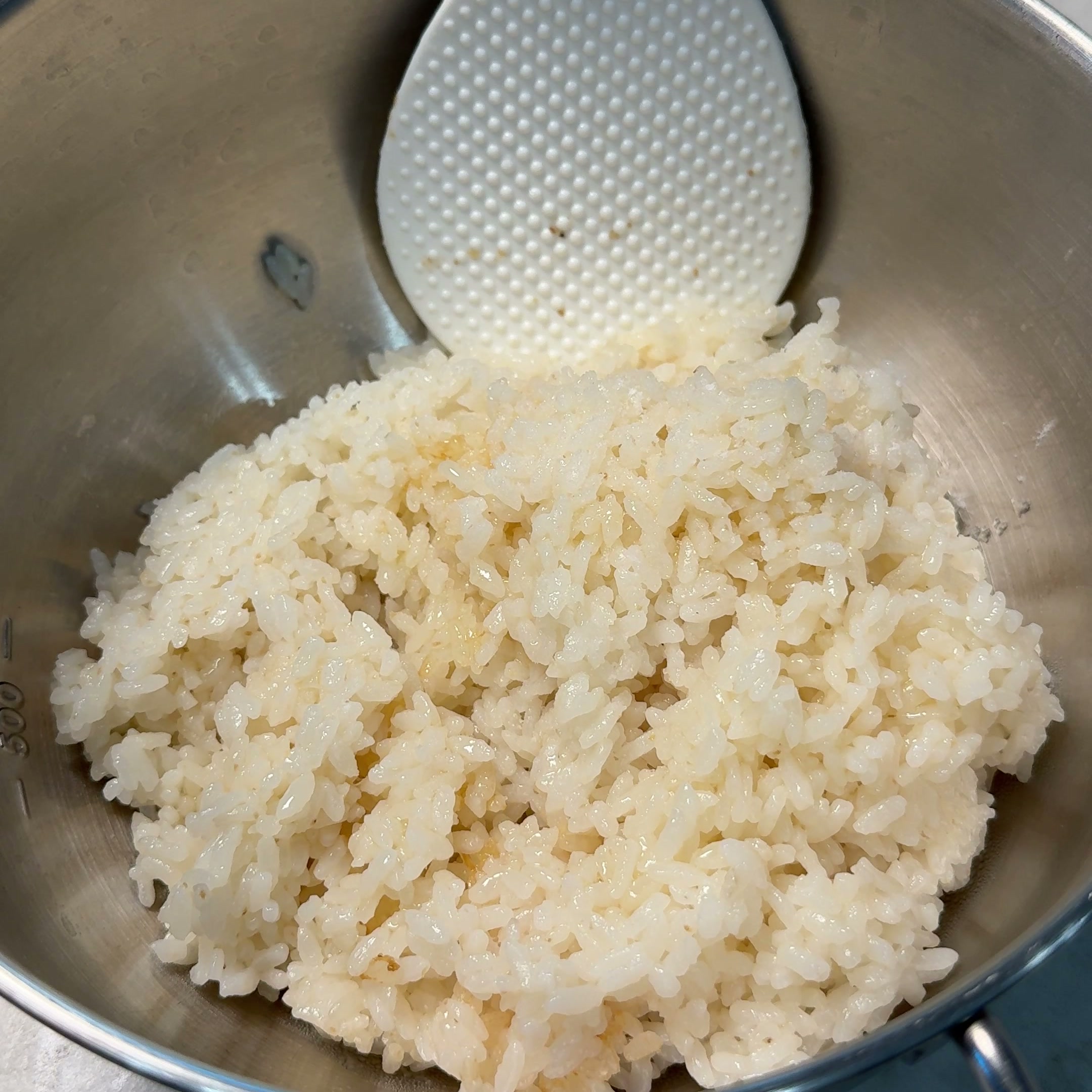 Rice seasoned with salt and sesame oil, mixed with a spatula