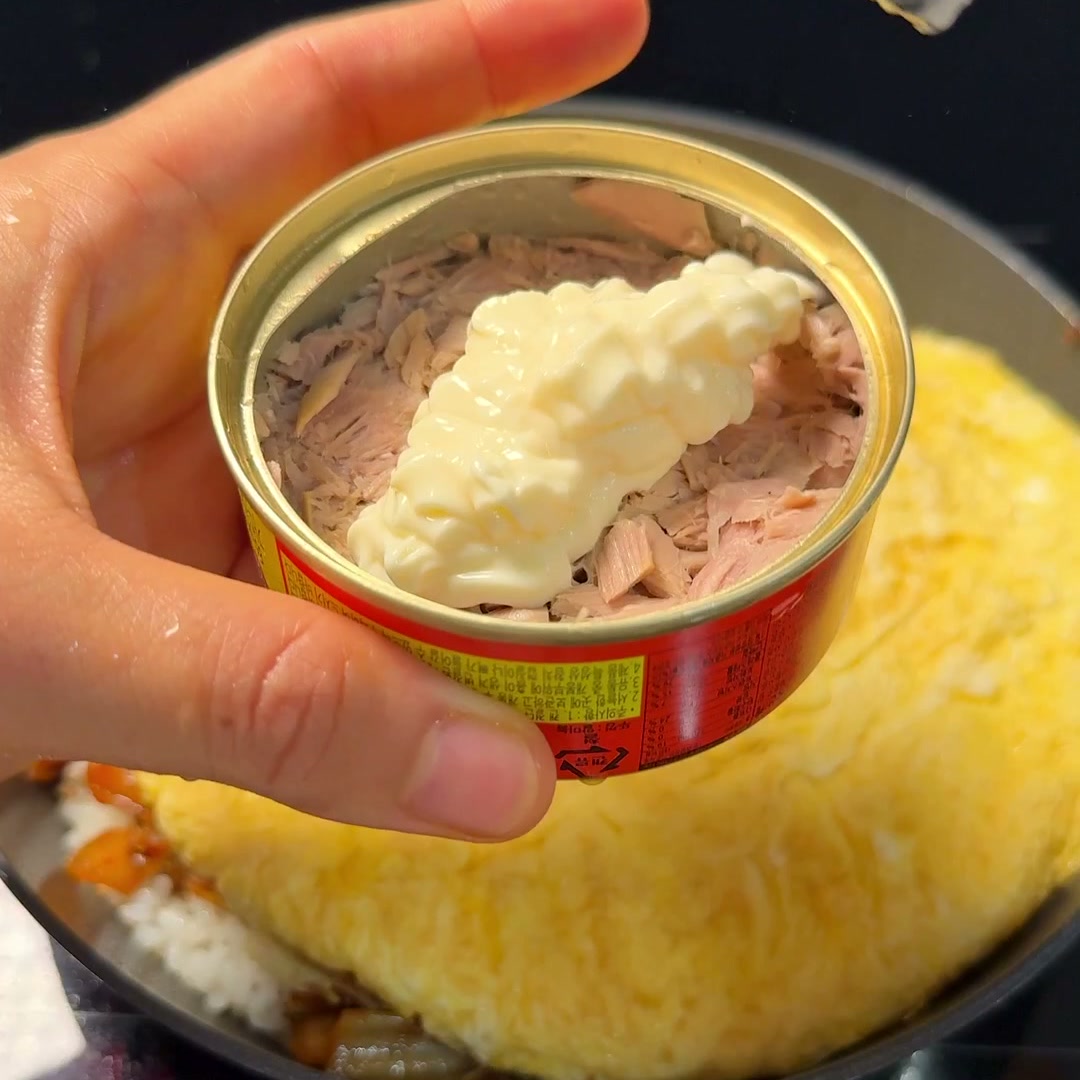 Mayonnaise mixed into canned tuna, held over the pan