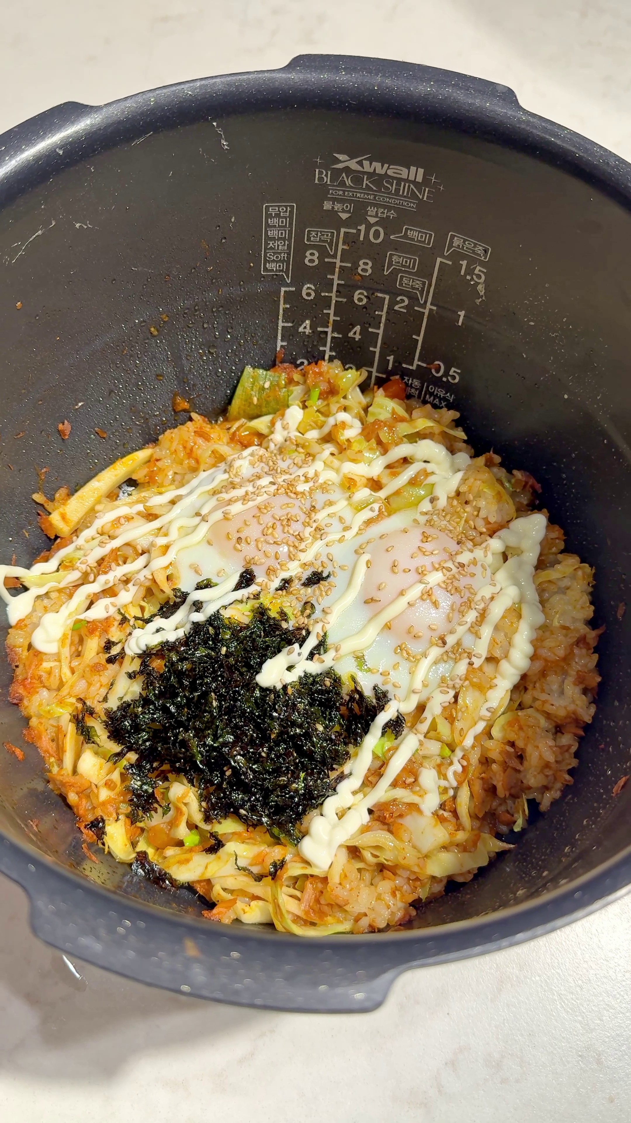 Spicy tuna and cabbage rice in a rice cooker topped with egg, mayo, and seaweed flakes