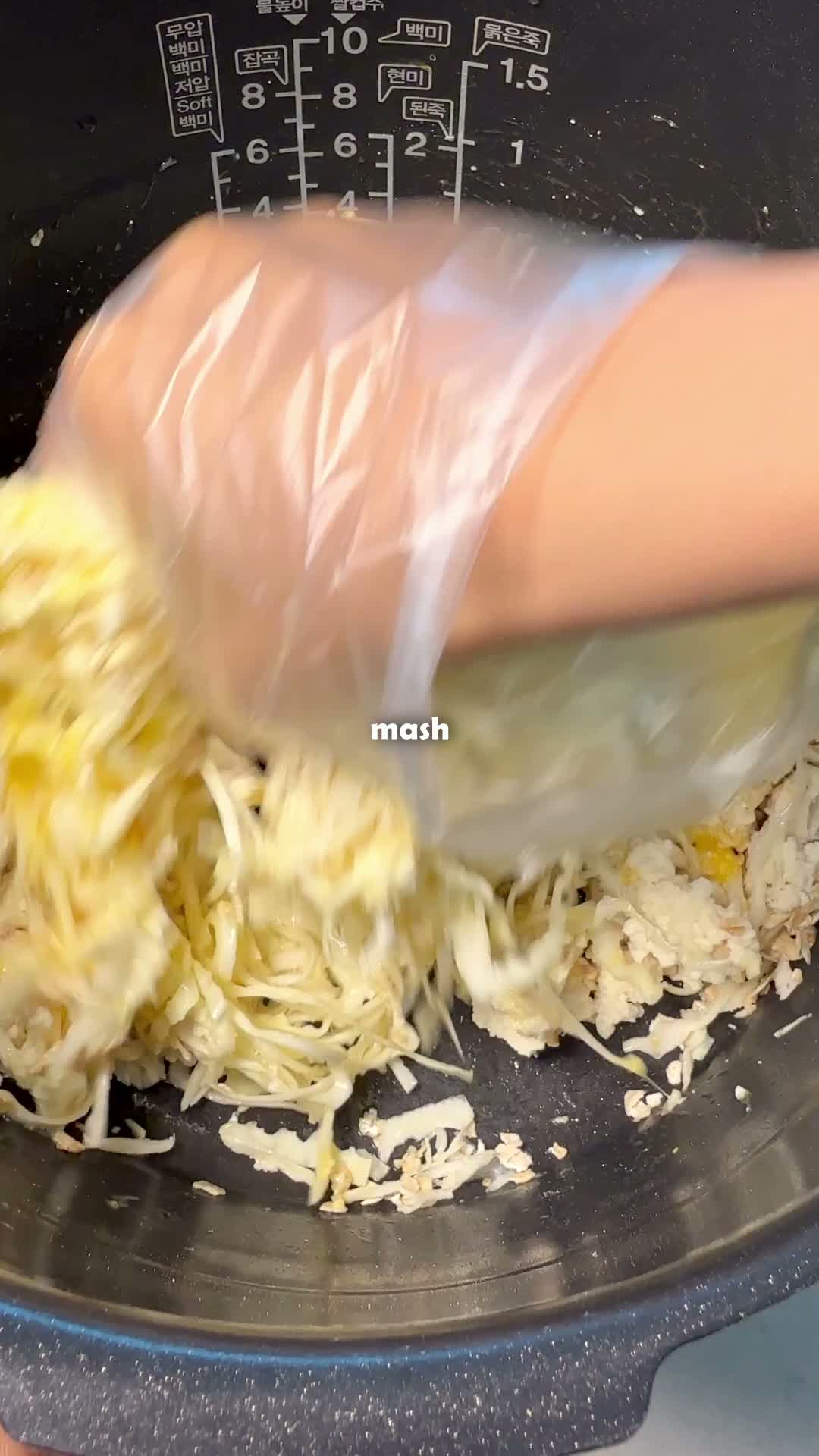 Mashing tofu, egg, and shredded cabbage together by hand in the rice cooker pot