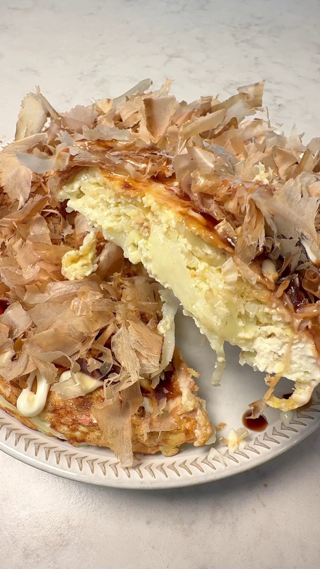Tofu okonomiyaki cross-section topped with bonito flakes