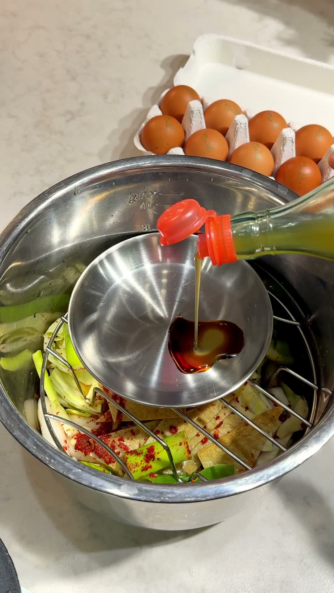 Dumplings and eggs arranged on a steam rack above the pot