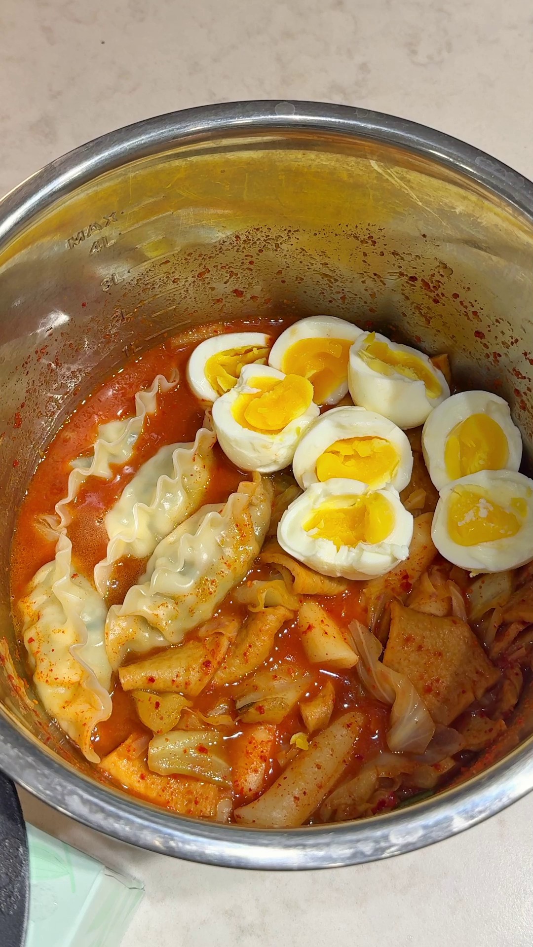Tteokbokki with rice cakes, fish cakes, dumplings, and soft-boiled eggs in a pot