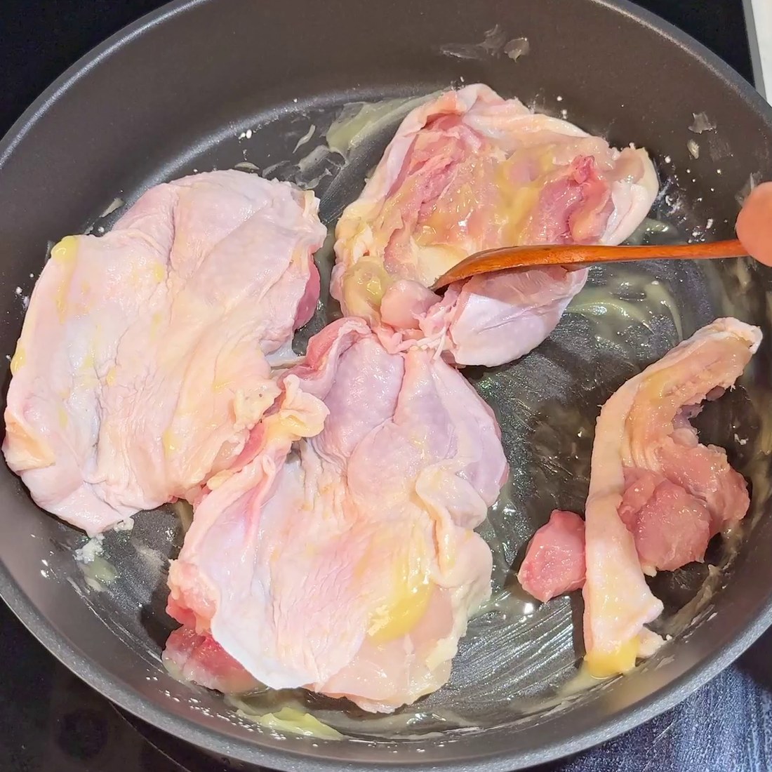 Chicken thighs spread skin-side down in the pan