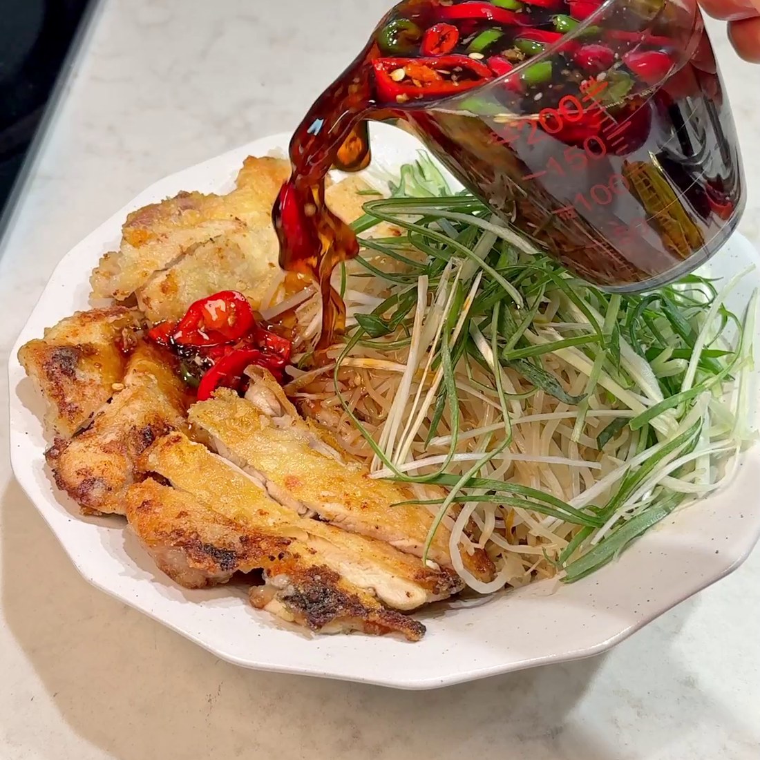 Finished bowl with chicken, bean sprouts, and sauce poured over